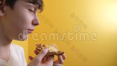 披萨。 快乐的青少年男孩吃一片披萨的概念。 十几岁的男孩饿了，吃一片比萨饼。 慢动作